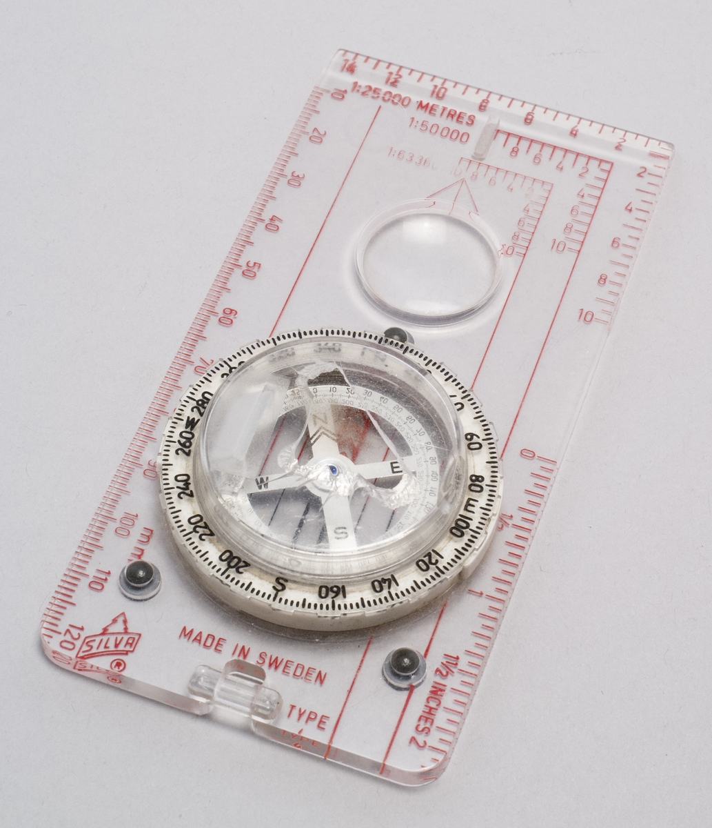 Kompass av typ 4, med lins och spegel för avläsning.  Text bifogad föremålet: "Med hål av isbjörnsklo under expeditionen på Grönland 2004 / Göran"