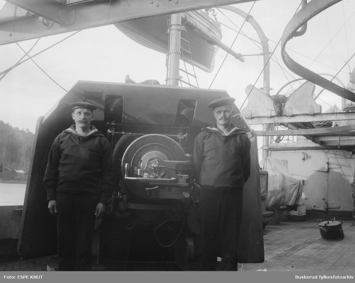 To gaster foran en skipskanon på D/S Eidsvold
Detaljer i bildet tyder på at dette er babord midtere 15cm kanon på panserskipet Eidsvold (eller Norge).  P/S Eidsvold ble bygget i 1901 og gikk tapt 9. april 1940.