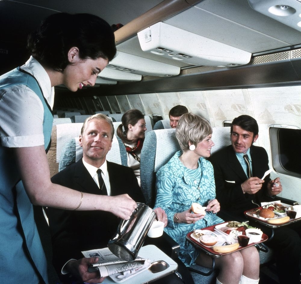 I kabinen til et fly fra Braathens SAFE, serverer flyvertinnen mat og kaffe til fornøyde passasjerer.
