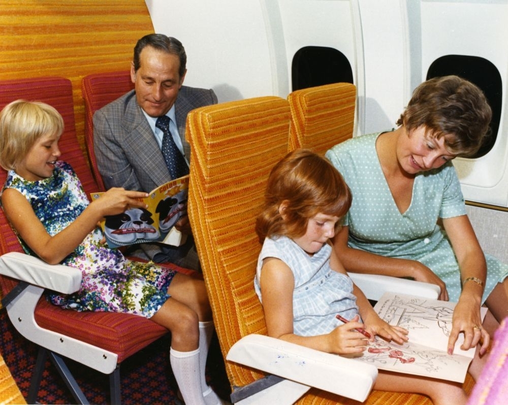 Luftfoto. To voksne og to barn koser seg ombord i et fly, DHC-7, Dash7, som gjennomfører en demostrasjonsflyging.