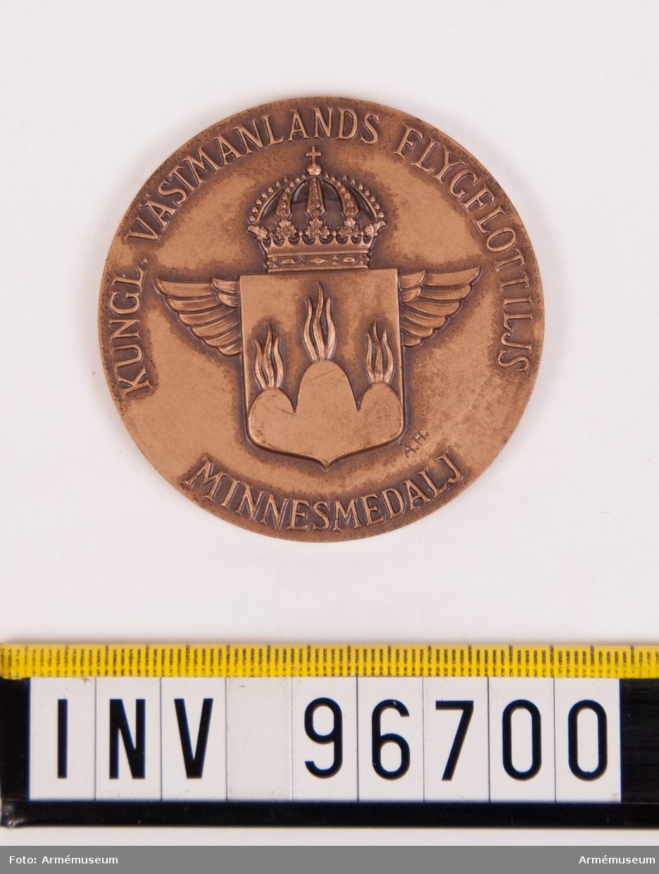 Medalj i brons för Västmanlands flygflottilj. Minnesmedalj.
Medalj upptagande Västmanlands vapen krönt av kunglig krona och lagt över vingar, enligt modell av Åke Hammarberg.
Stans nr 26498, 2745.
Stans härdad 1959-08-26.