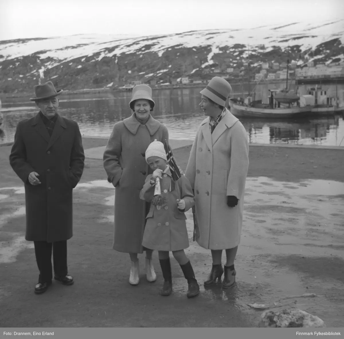 Fire personer på Dampskipskaia i Hammerfest, sannsynligvis 17. mai siden jenta har flgg og fløyte i hendene. Jenny Drannem står helt til høyre på bildet, de tre andre er familien Sørensen.