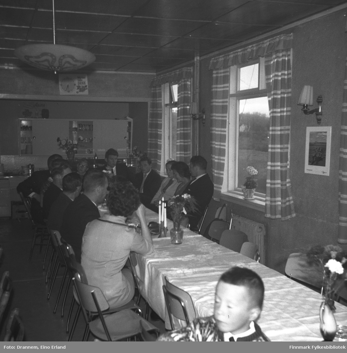 Mange personer sitter ved et langbord i et lokale i Neiden. Dette kan være fra Alfred Karikoskis begravelse i august 1965.