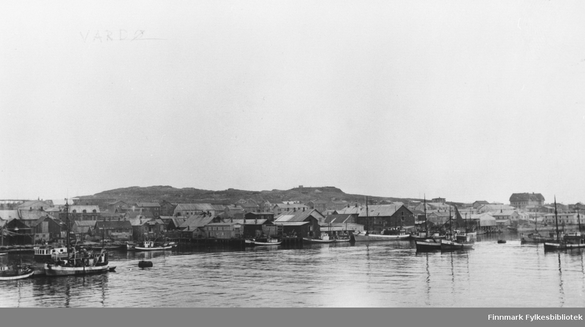 Havna i Vardø med fiskebåter og pakkhus. I bakgrunnen ser vi skolen. B 5747