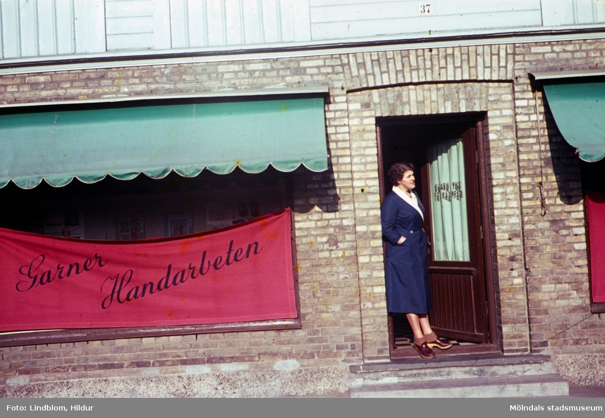 Tant Kajsa, d.v.s. Kajsa Forsell, står i dörren till Kvarnbyns Trikåaffär med adress Kvarnbygatan 37 i Mölndal, 1960-tal.

För mer information om bilden se under tilläggsinformation.