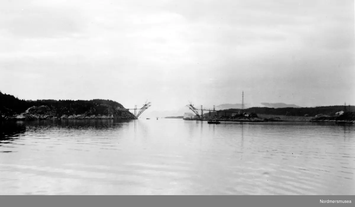 Omsund bru under konstruksjon. Omsund bru krysser Omsundet mellom øyene Frei og Nordlandet i Kristiansund kommune. Broen er 281 meter lang og ble tatt i bruk april 1940, men fikk ingen offisiell åpning på grunn av utbruddet av 2. verdenskrig. Broen ble prøvd bombet av tyskerne, men holdt, men 15 år gamle Ingolf Vatten som syklet over broen da tyskerne bombet broen ble drept. Broen var også viktig da Kristiansund ble evakuert. Broen ble liksom åpnet offisielt 24. april 2005, 65 år etter at den ble tatt i bruk. Per i dag 2008 er denne broen bare åpen for fotgjengere og en ny bro ved siden av den gamle er blitt bygd. Denne er en del av riksvei 70. Fotograf er usikk, men sannsynligvis Georg Sverdrup. Fra Nordmøre Museums fotosamlinger. Kilde: http://no.wikipedia.org/wiki/Omsundbrua
