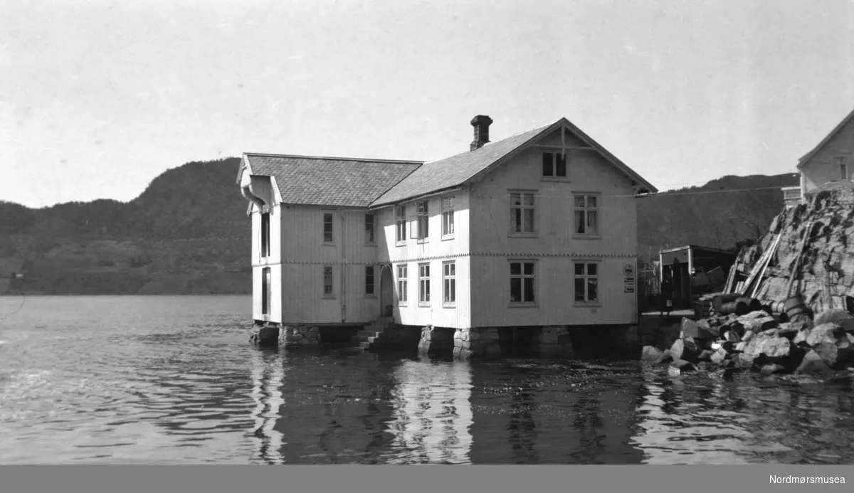 Foto av en brygge liggende helt nede ved sjøkanten usikkert hvor, men trolig i eller like ved Kristiansund. Datering er også usikker, men sannsynligvis omkring 1920 til 1939. Fra Nordmøre museums fotosamlinger.
