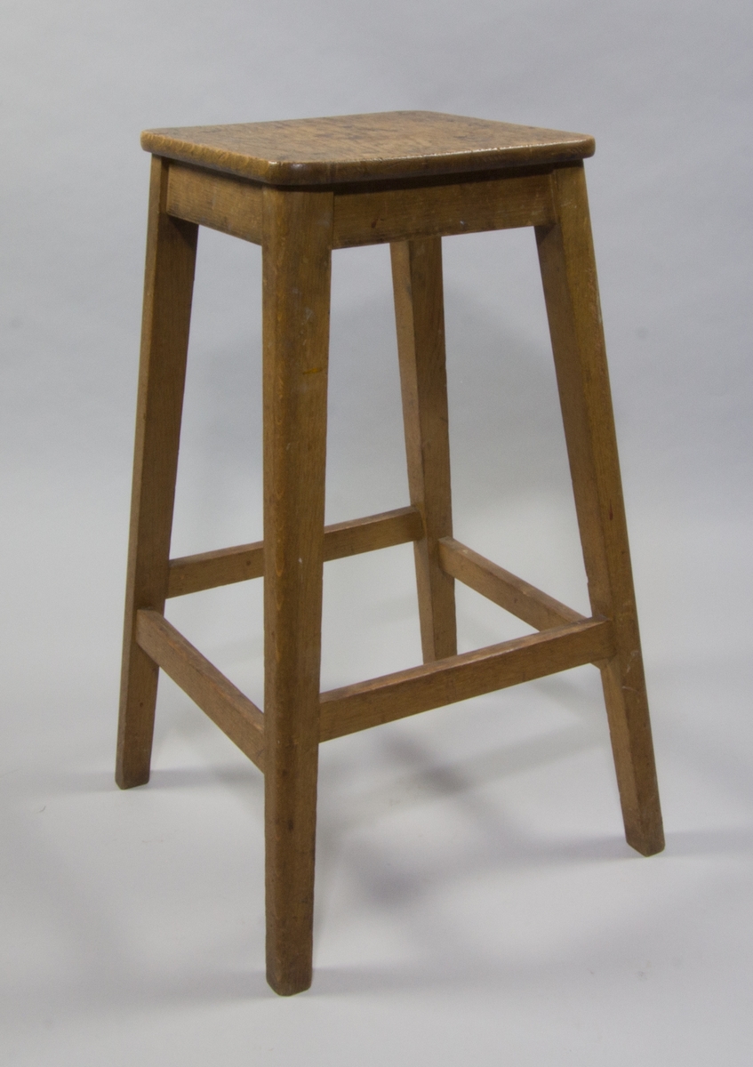 Stol, pall av ek med fyra lätt utställda ben och plan kvadratisk sits. Smärre fläckar på sitsen.