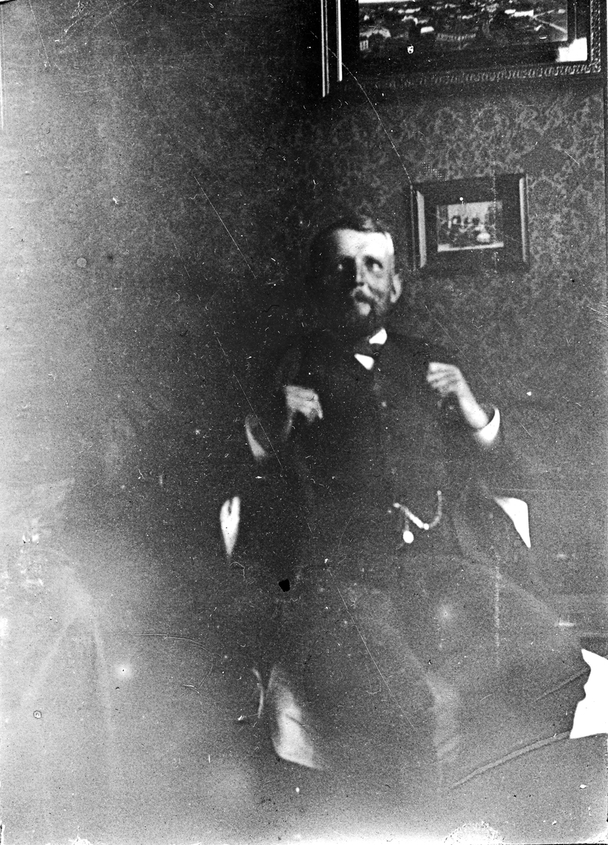 En man som sitter i en fåtölj. Fotograf Alfred Bergendahl. Givare H Bergendahl.