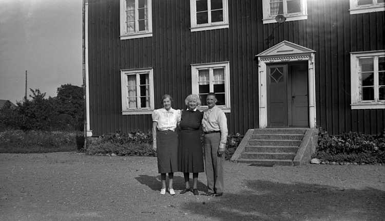 Foto på prästgård med två kvinnor och en man framför.