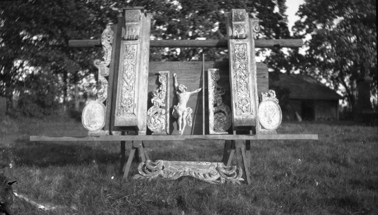 Foto på ett nedmonterat större krucifix, några delar till en
läktare, dekorationer m.m. utomhus.