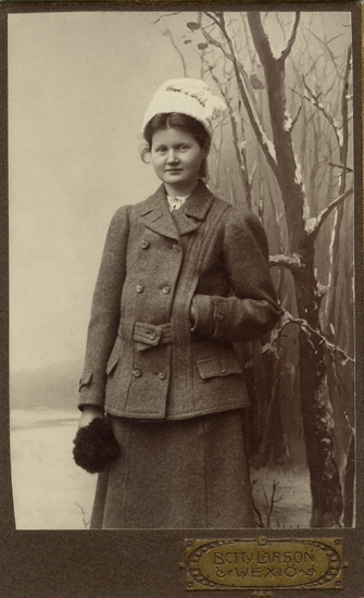 Porträtt (knäbild, en face) av en ung kvinna, klädd i enkel
promenaddräkt med en stickad mössa på huvudet.


Ellen Ekedahl (1891-1911) var dotter till domprosten Esaias Ekedahl (1856-1926) , Växjö och hans hustru Cordula, 
f. Andersson (1851-1943).