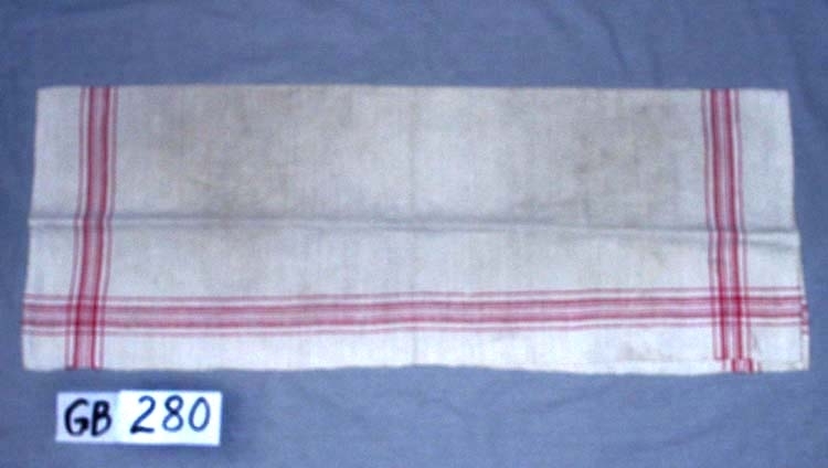 Handduk. Handvävd.
Kvalitet: halvlinne, bomull i varp, oblekt och rött, dubbelt.
Fållar: 0,5 cm, handfållade.
Hängband: handvävt, Vitt med en röd rand, 0,7 cm brett, 
5 cm långt, 2 st.
Varpordning till bård:
Rött:     2 4 2 2 4 2
Oblekt:  6 2 4 2 6
Inskrivet i huvudkatalogen 1996-1997.