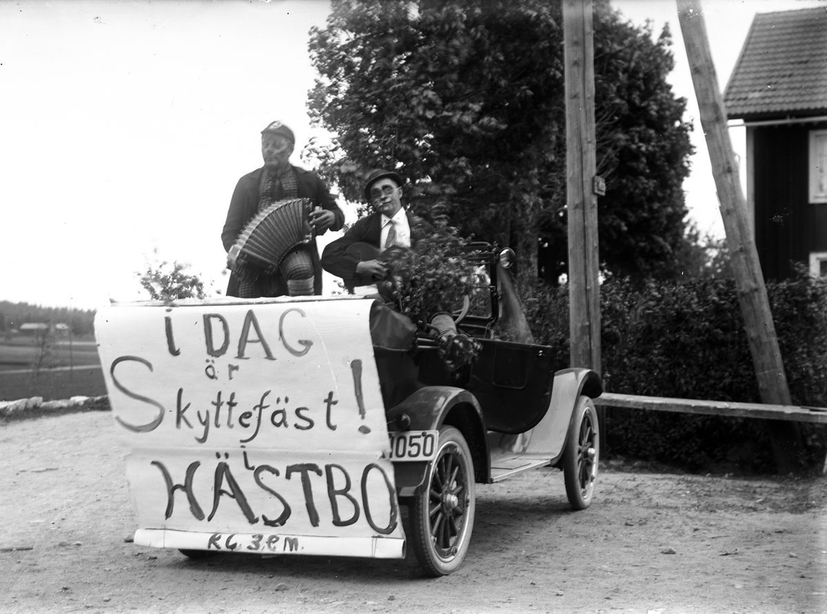 Reklam för "Idag Skyttefäst i Hästbo, kl. 3 em". Josef Eriksson, Hästbo, med dragspelet i sin Overland bil av 1922 års modell.