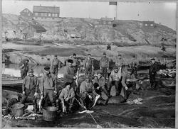 Fiskere som sløyer fisk ved Hamnakeila på Husøya i Halten ca