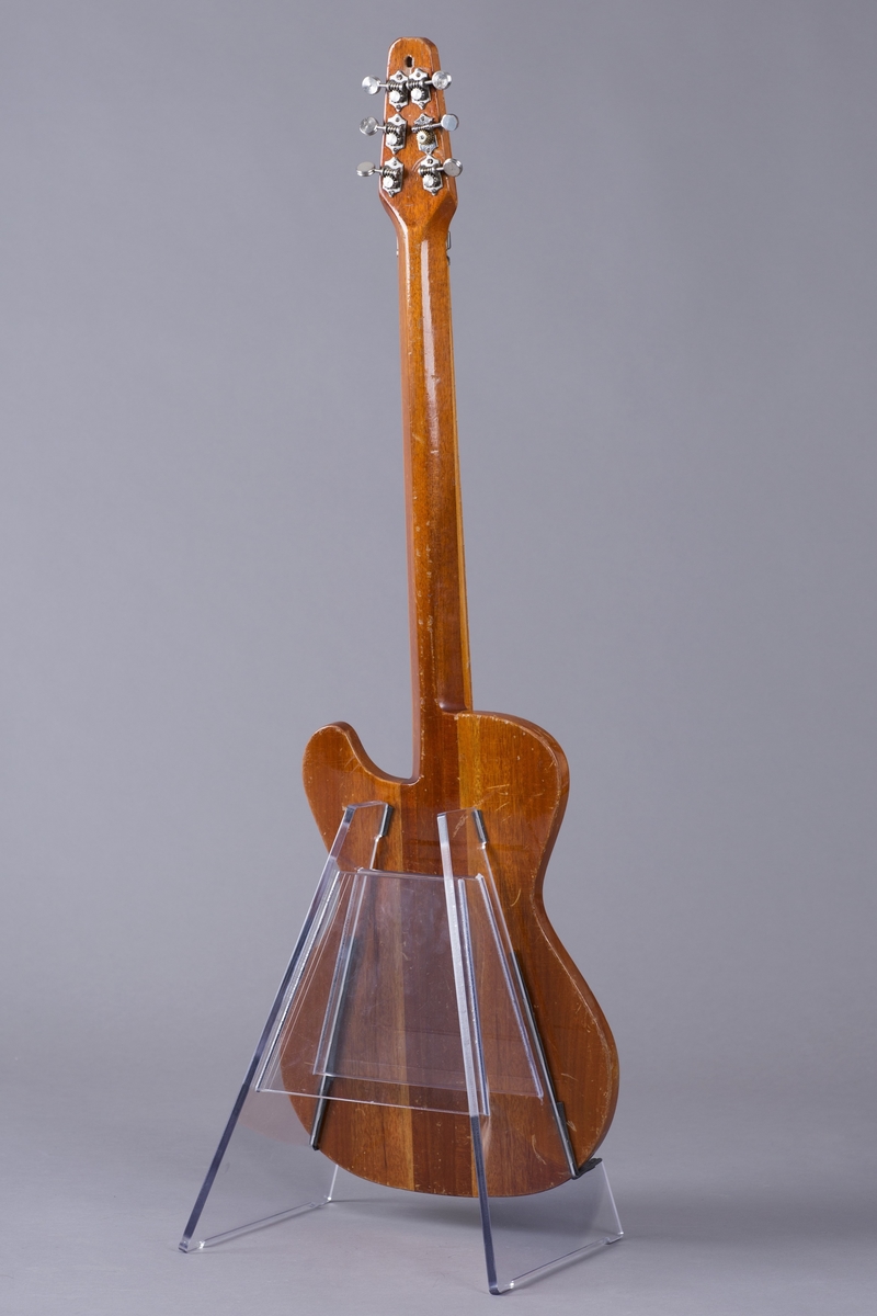 Elektrisk gitar med kropp og hals av mahogny. Magnet ved halsfeste og pickup ved strengefeste (NilsensSystem). Kontrollere for tilpasning og klangfarge. Tilpasning tilsvarer volum og gir størst volum på nivå 1. Enkelte av stemmeskruene er ikke originale.