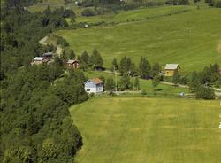 Flere bolighus i utkant av dyrka mark.