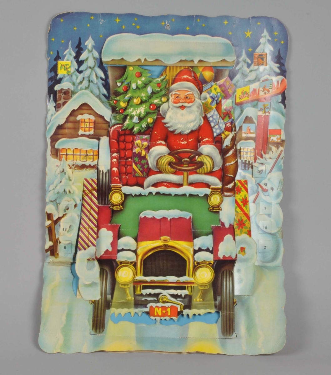 Motivet er en julenisse som kjører bil - N1. Den er lastet med juletrær og presanger. En snømann i forgrunnen. Et hus på hver side av bilen.