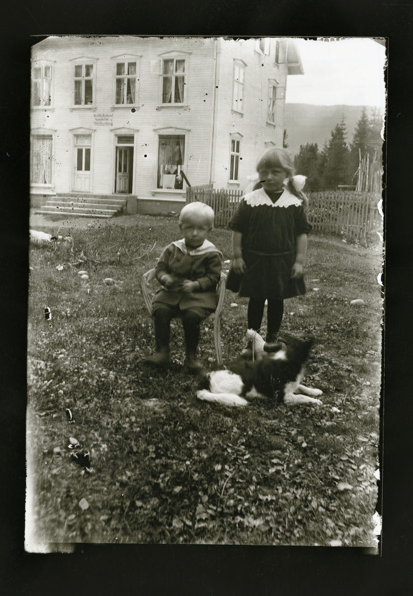 To barn står foran ett hvitt hus som var en motebutikk.