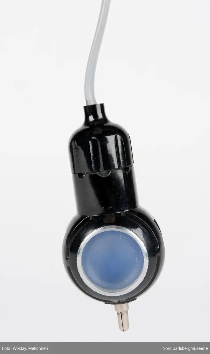 En liten lampe med to sider; en med blått lys, en med dempet lys. På toppen en metallpinne (el-kontakt?)Nyere ledning med bryter påmontert. Usikker bruksmåte og formål.