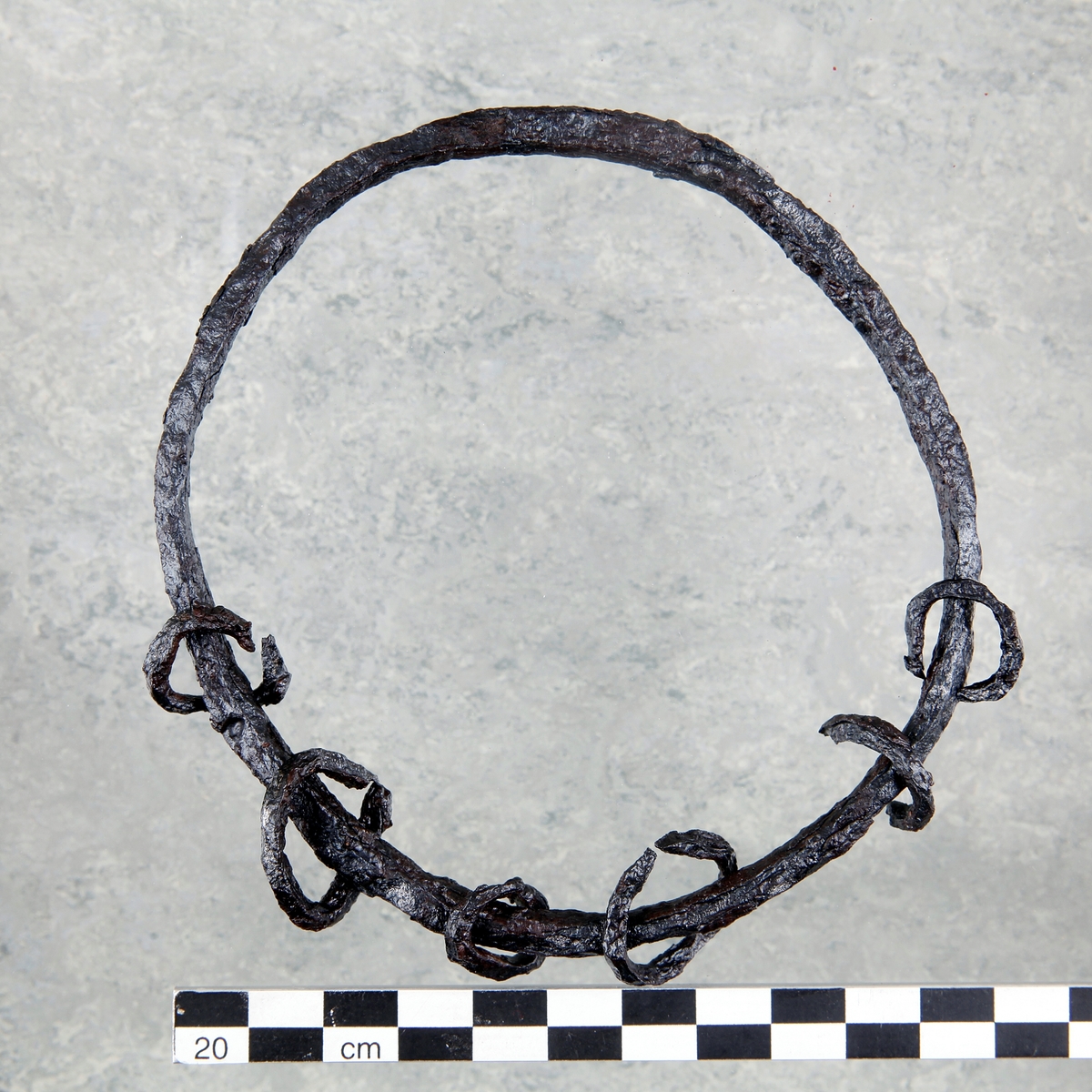 Amulettring av järn. Rund ring med sex mindre ringar på. Vissa ringar ej kompletta. Har ursprungligen varit fler ringar, nu fragmenterade.