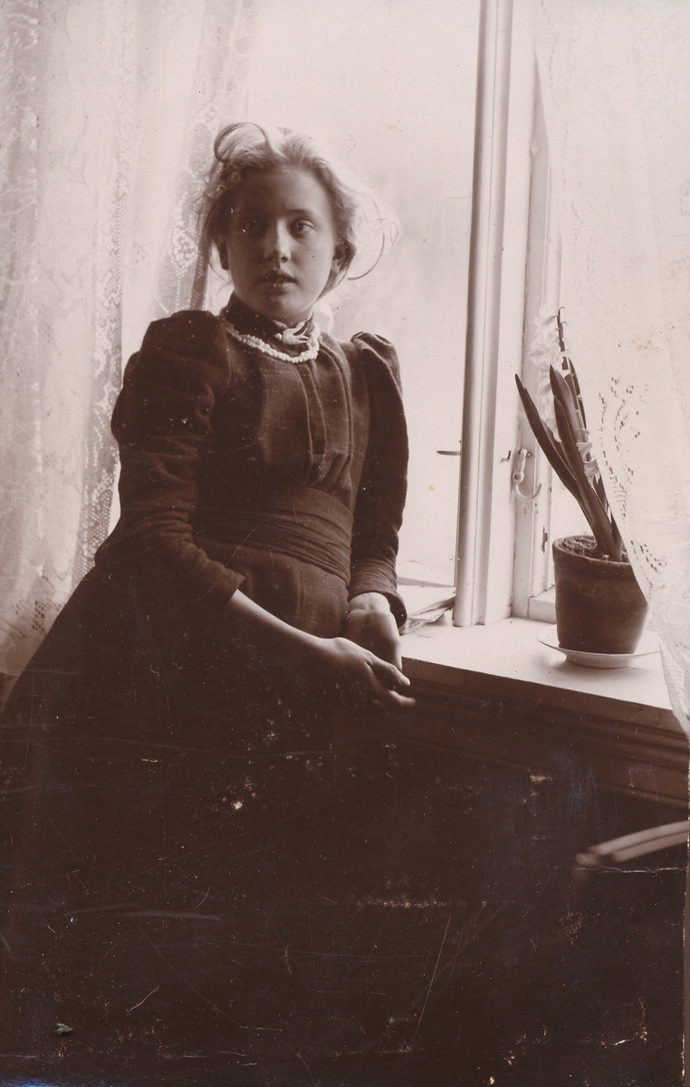 Portrett av ung pike ved vindu.