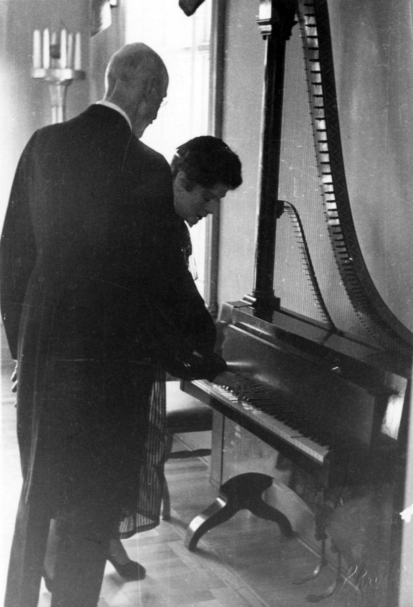 Kong Haakon VII besøker musikkhistorisk museum. Victoria Bachke viser frem en pianoharpe.
