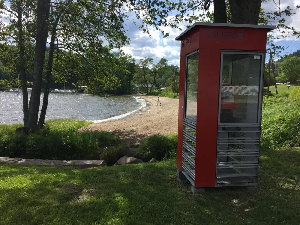 Rød telefonkiosk ved badestrand i Hyggen