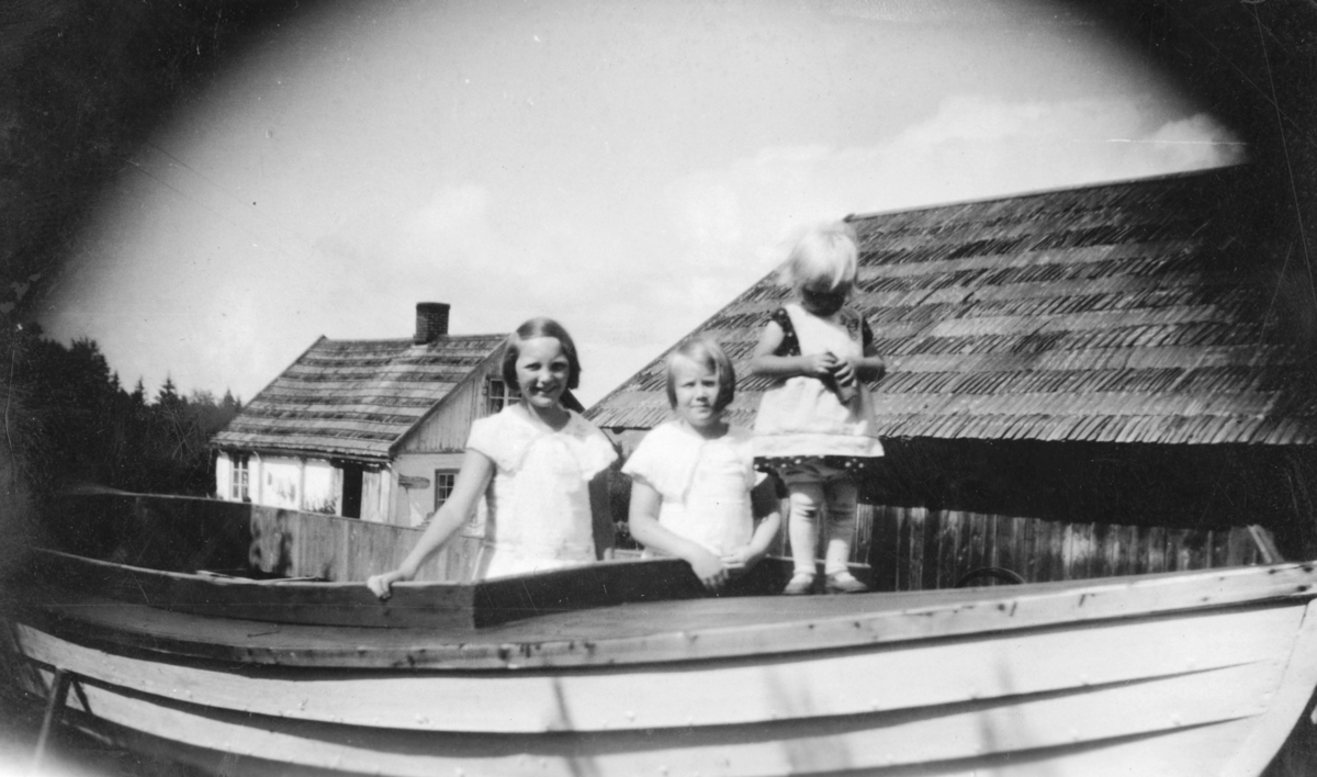 3 småjenter i båt på gardsplassen i Rønningen, Helgøya. Fra venstre er Evelyn, Åse, ukjent.