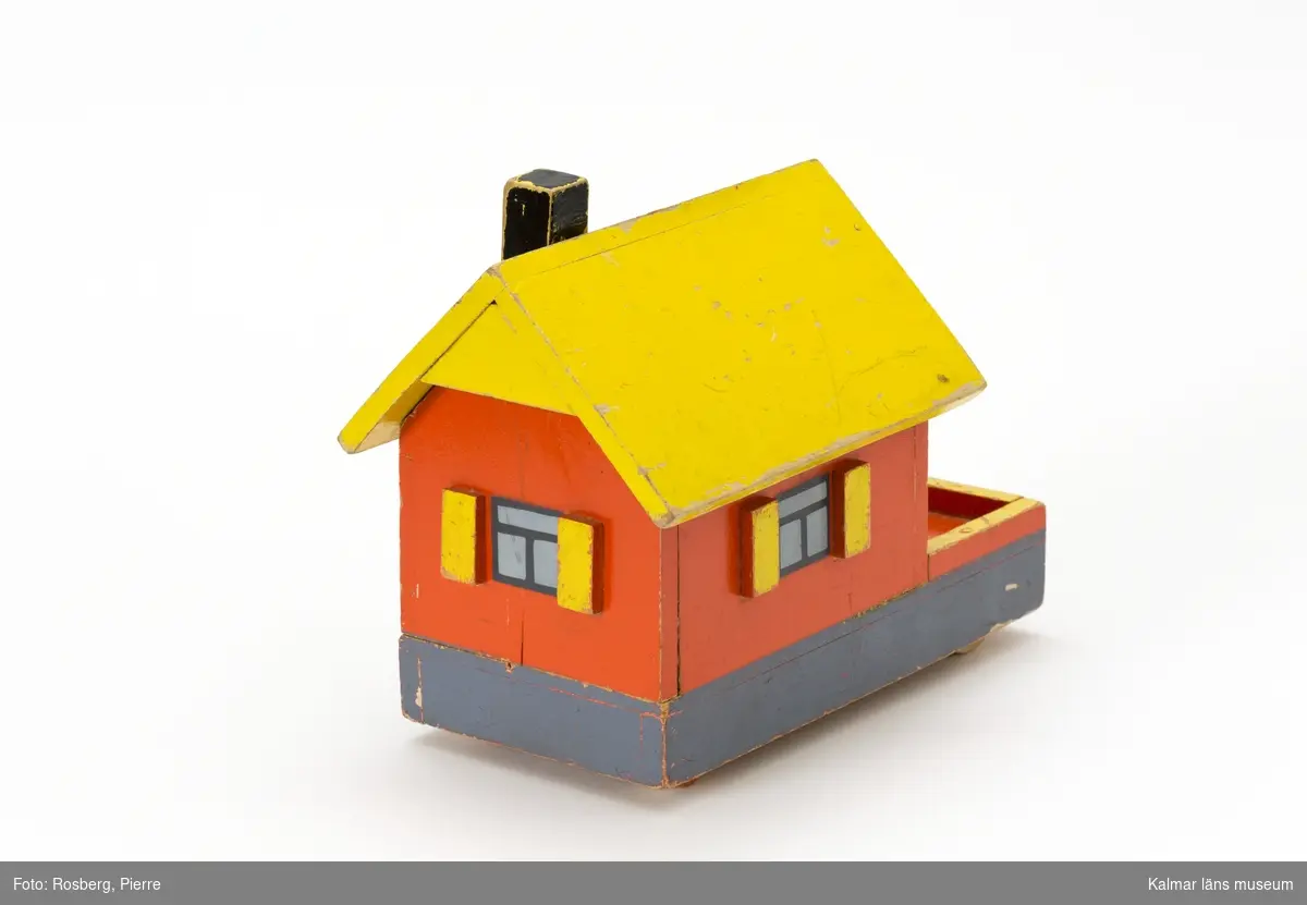 KLM 45110:2. Hus på hjul, leksak, av trä. Taket fungerar som ett lock och går att ta av. Huset målat i rött, gult och svart. På undersidan text: 516 samt 2 kr.