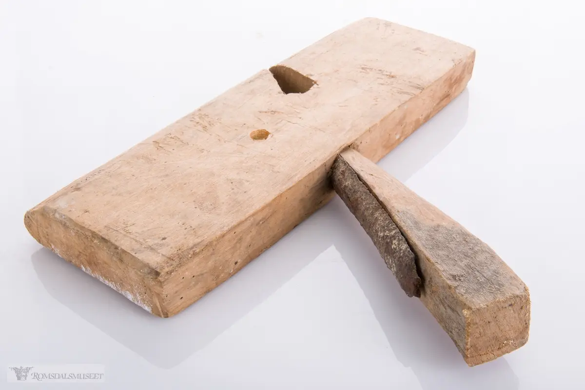 Enkel høvel skåret ut av et stykke tre som er avrundet under. Langt avrundet jern og utskåret kile.