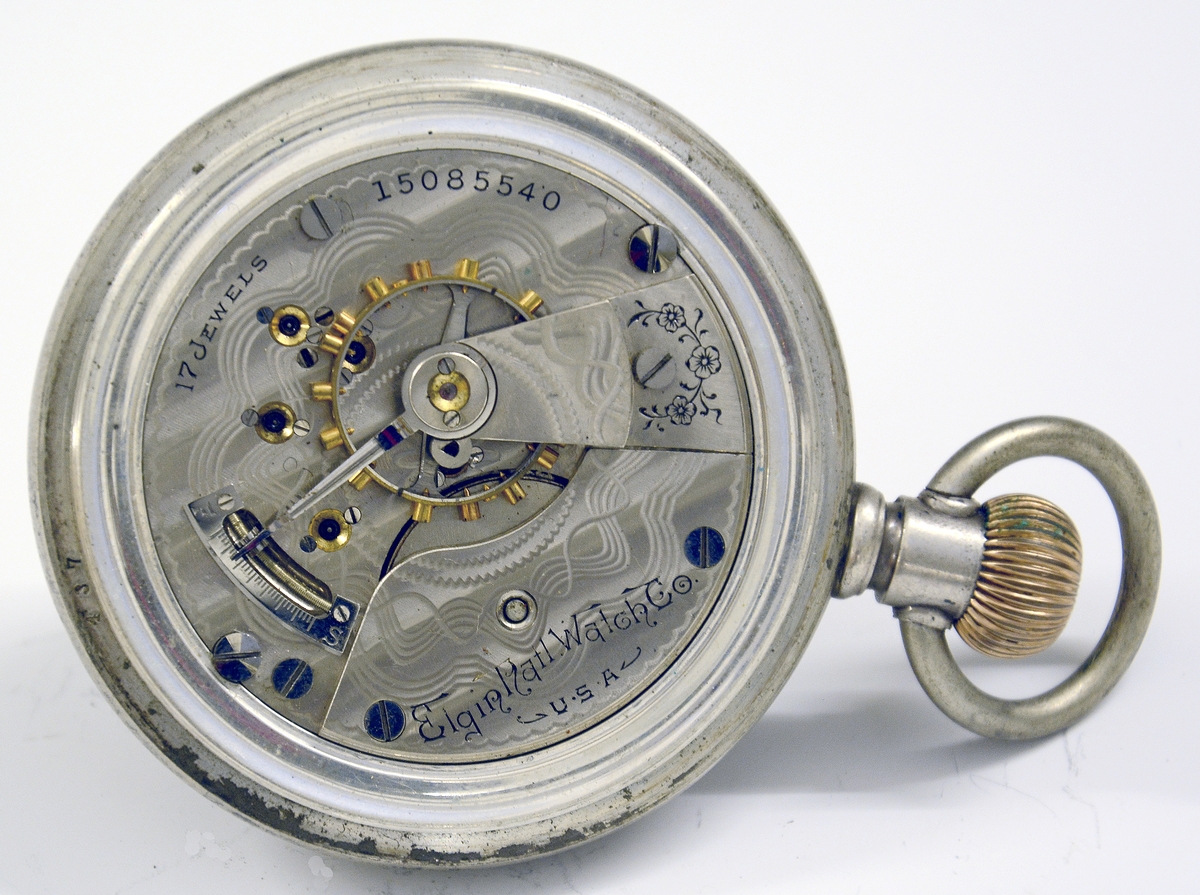 Amerikansk lommeur, større og flatere enn de eldre urene. Uret trekkes opp ved bøylen. Blant de første standardiserte urene som førte til masseproduksjon. Mrk Elgin. Hjort innlagt i bronse på baklokket.