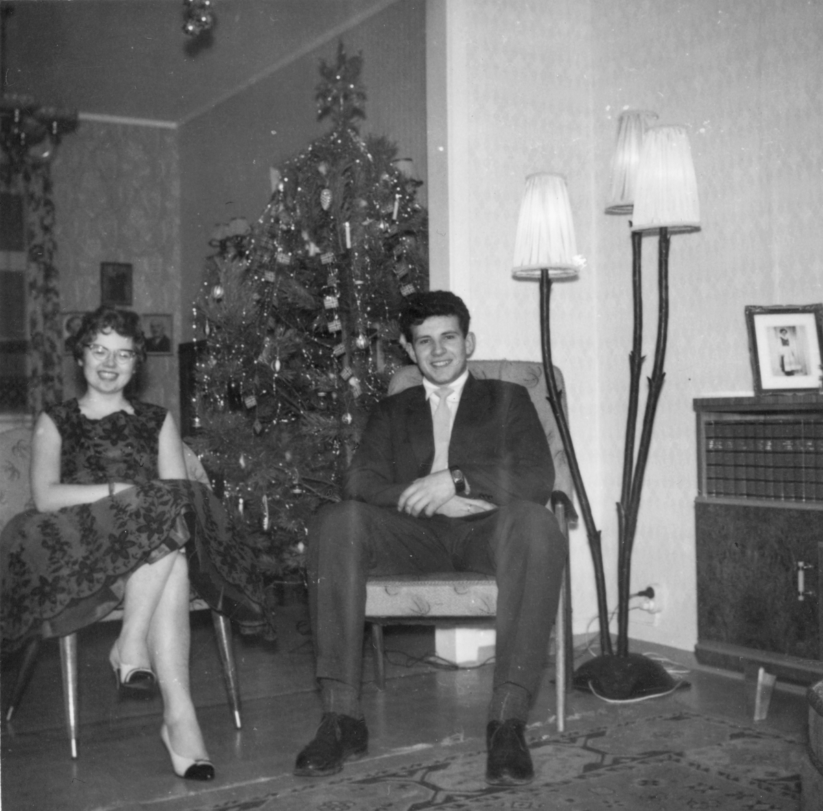 Kvinne og mann i ei stove med juletre.