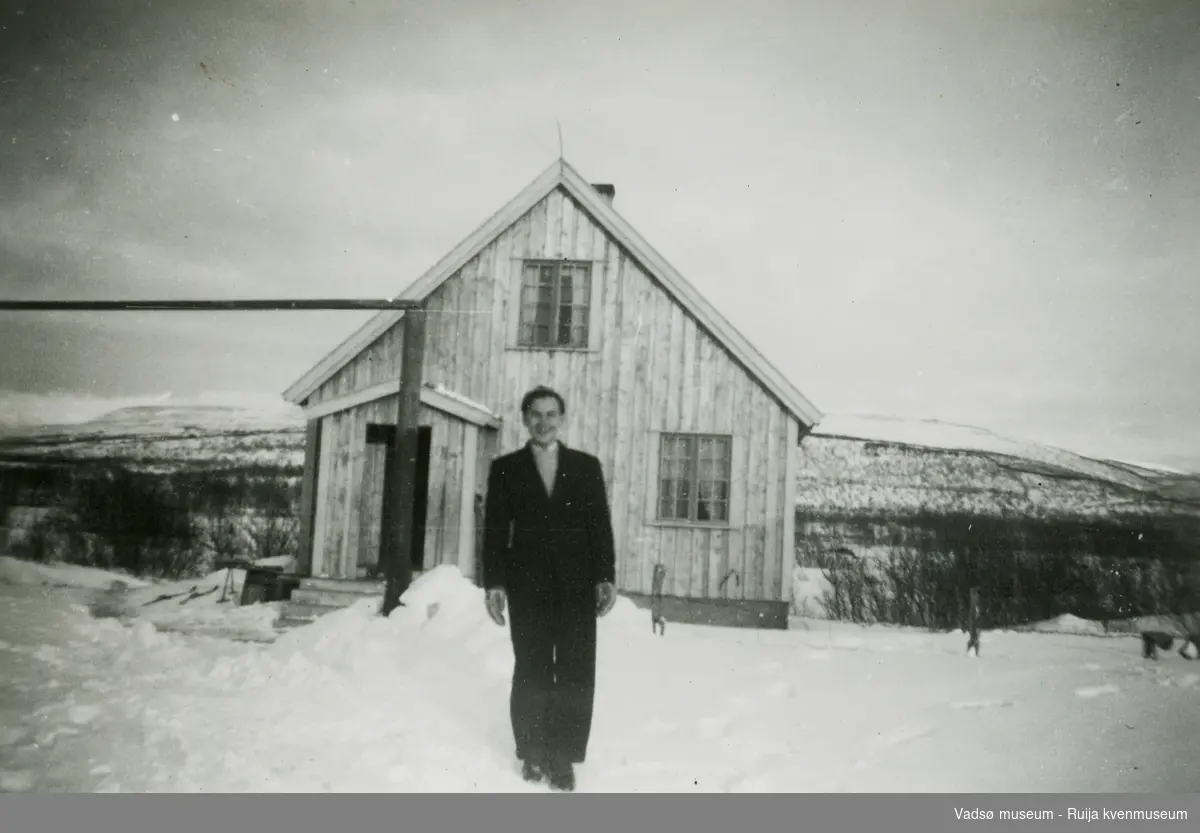 Mann foran et gjenreisingshus vinterstid. Antatt sted Vestre Jakobselv, ca. 1948.