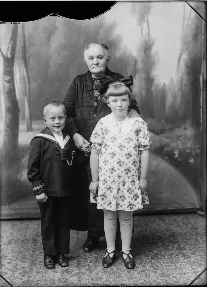 Studioportrett av eldre kvinne med to barn.
