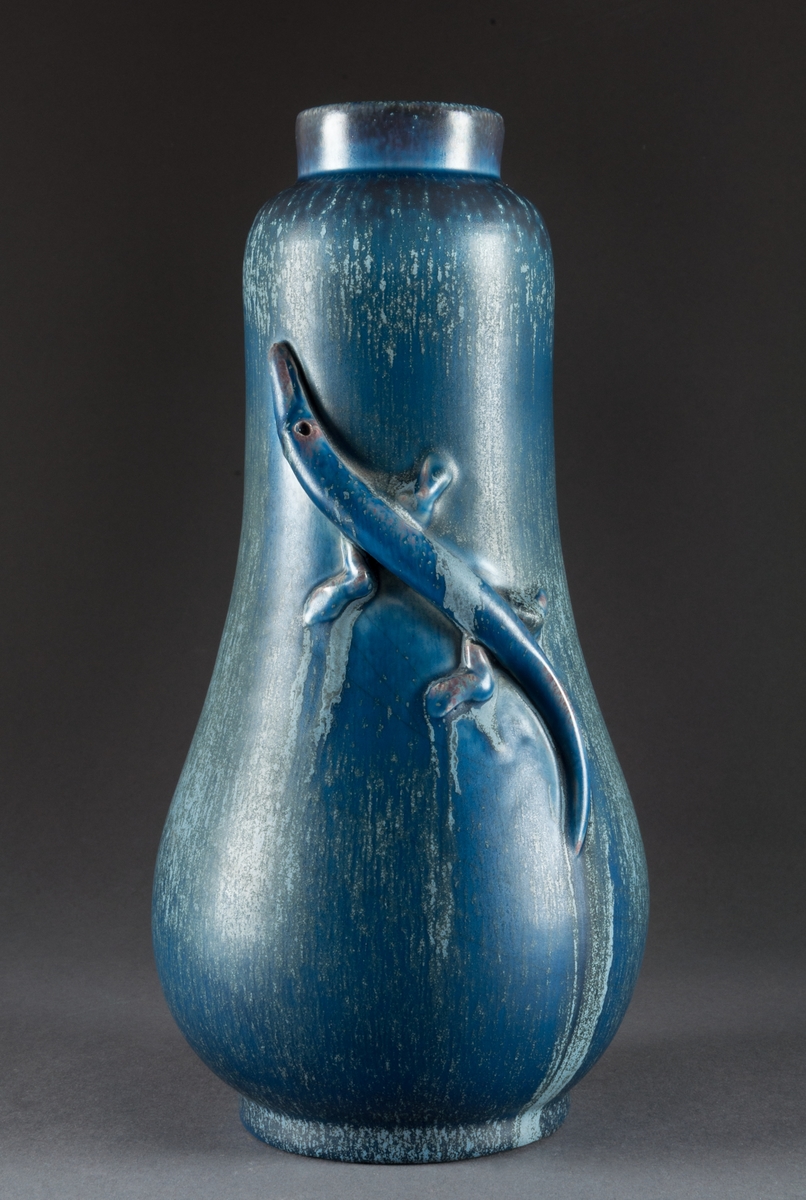 Vas, höjd 28 cm, blå och blågrön atomglasyr, GK15. Denna glasyr tillverkades/användes främst åren 1938-39. Formgivare Ewald Dahlskog, Bobergs Fajansfabrik, Gävle. Otydlig märkning.