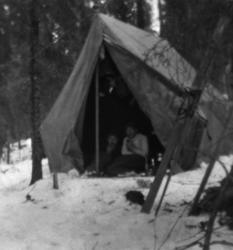 Foto av to menn på telttur en vinterdag. Muligens på oppdrag