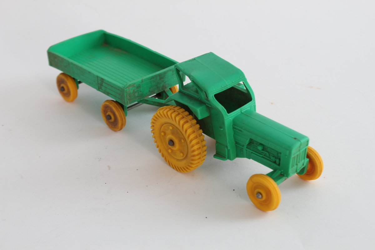 Giver. Bjørn Sverre Hol Haugen (f.1972).
En grønn traktor med gule hjul og henger, i plastikk.