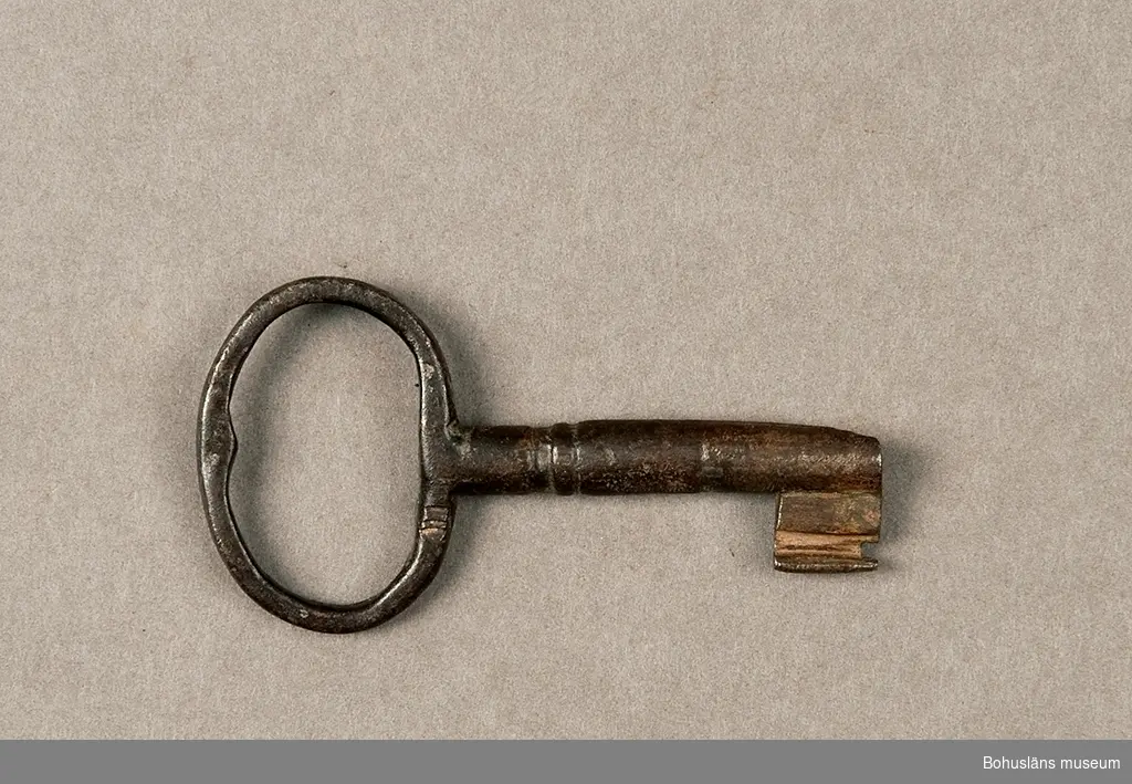 Ur handskrivna katalogen 1957-1958:
Järnlås m. nyckel, hänglås
Låset (A) mått: 11,5 x 7,8 x 3,5 cm; järn; helt. Nyckeln (B) L. 8,2 cm; järn. Något trasig. Föremålen något rostiga.