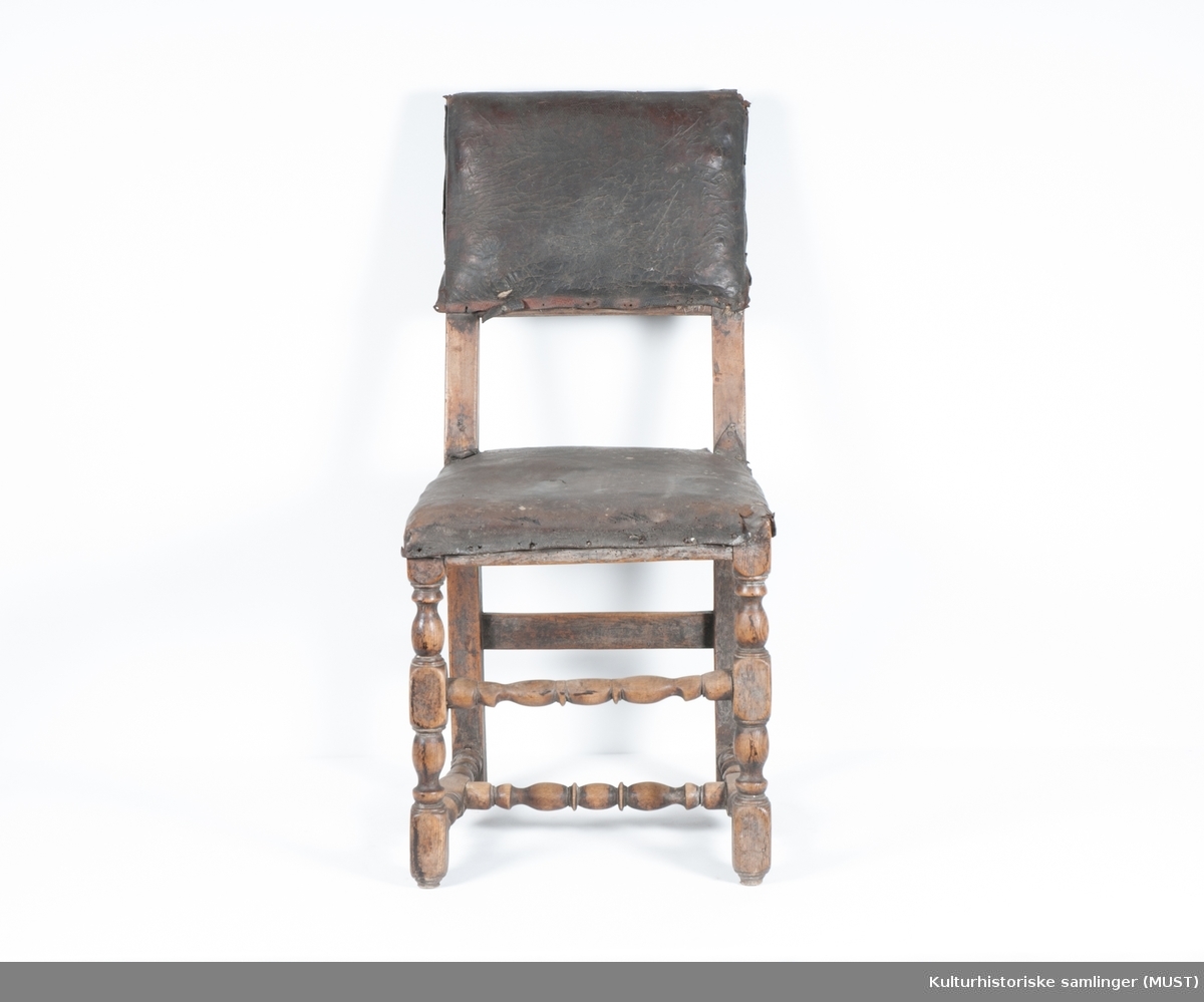 Fast sete. Setet og rygg er trukket med svart skinn, antagelig originalt. Stolen har dreide forbein og sprosser.