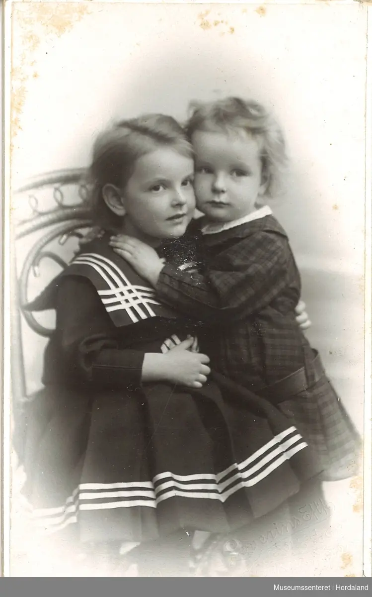 atelierfotografi av to små barn, jente med matroskjole og gut kledd i ruta kjole