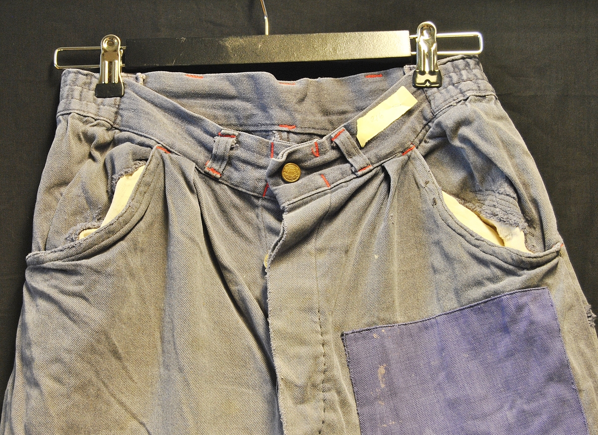 Arbeidsbukse av dongristoff. Bærer preg av bruk. Lappet flere ganger.