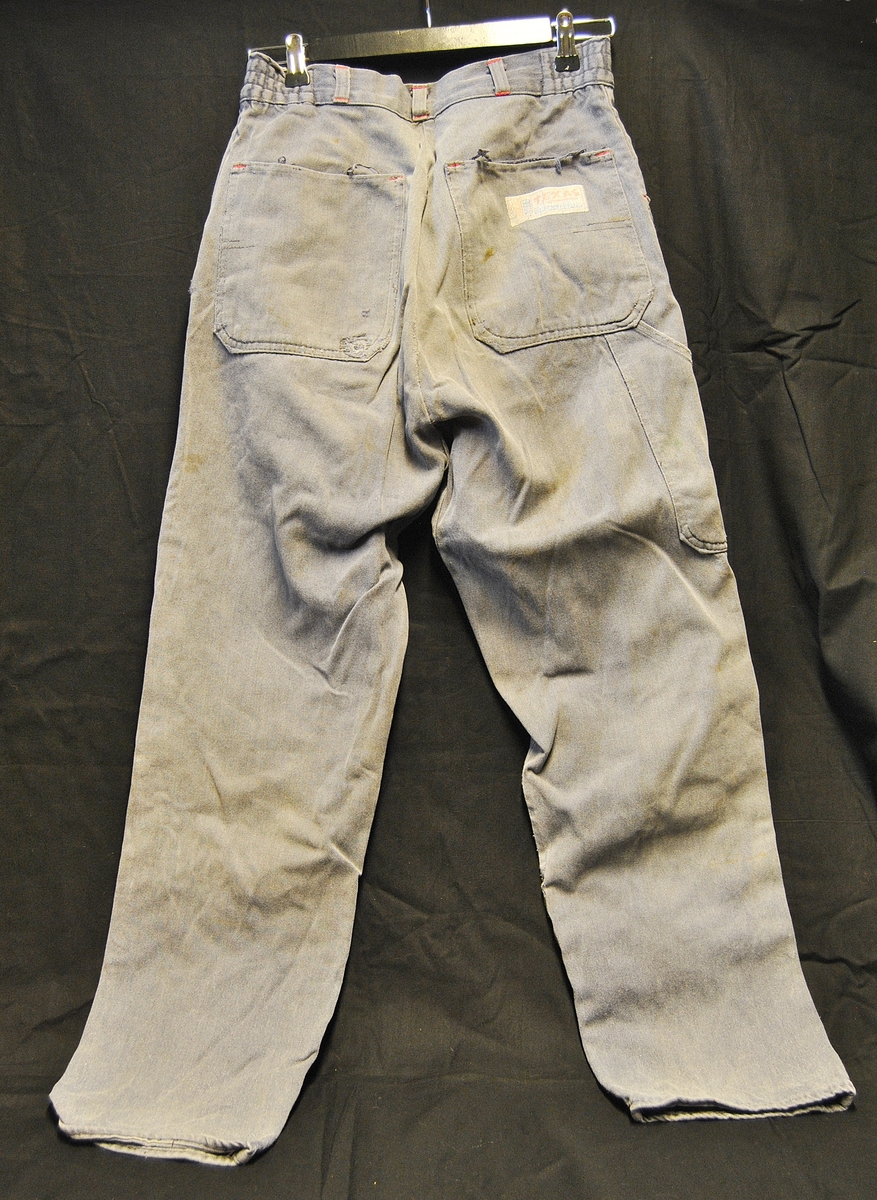 Arbeidsbukse av dongristoff. Bærer preg av bruk. Lappet flere ganger.