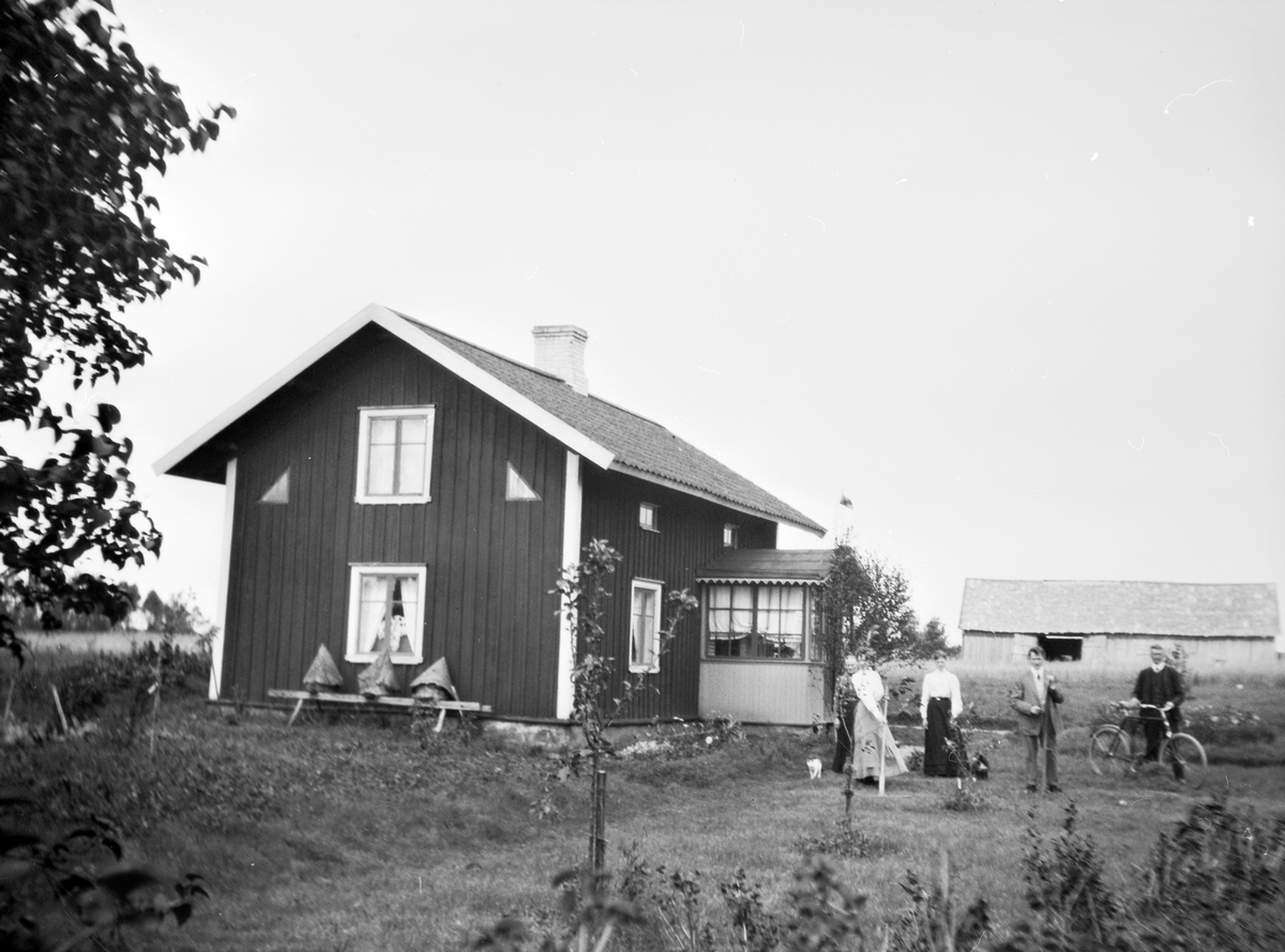 Några människor vid ett hus vid Västra Jära Norrgård.