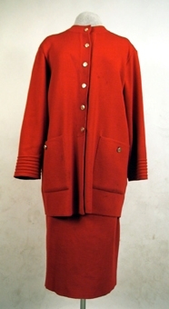 Röd maskinstickad kjol av ullgarn med tillhörande kofta (106259:1).
Slits med två knappar mitt bak. Resår i midjans linning.
Har tidigare tillhört dottern Elisabeth (givaren)