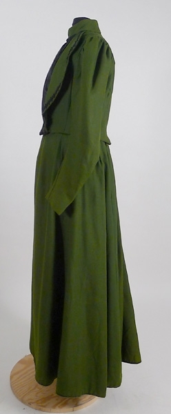 Enligt liggaren: Klänning, (klänningsliv och kjol) av grönt ylletyg med svart besättning.