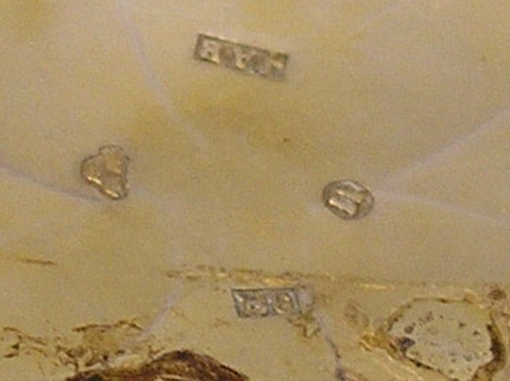 Enl. liggare:
"Luktdosa av silver i urform. På ena boetten en ingraverad palmett, å den andra CJs inom rombisk ram. Inuti en förgylld genombruten o. graverad mellanboett. Diameter: 4,3 cm. 
Stämplar: JAB.- Tre kronor-U-B6 (1880)