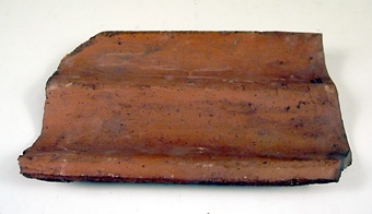 Taktegel av bränd lera, tvåkupig panna, mindre modell. L. 340 br. 230 tj 13 mm."

Okänd tillverkning