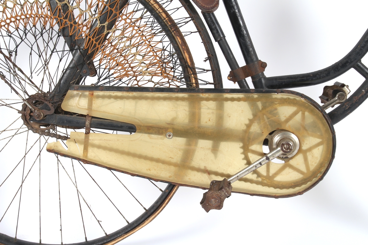 Svartlakkert damesykkel med dekkpumpe og taske til verktøy under setet og kjolenett på bakhjul. Sykkelen har Torpedo frinav med innebygd trommelbrems bak, og mekanisk bremse foran med klosse som går direkte på dekket. Svensk modell.