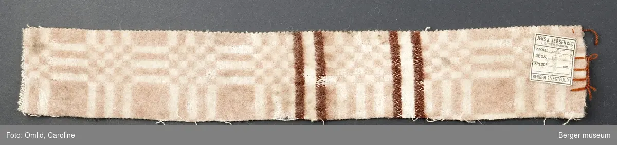 En prøve. Teppe med gjentagende mønster som blir brutt av samme mønsterbord i en annen farge.
Mønsteret er en ørliten variasjon over BMF.03587-C-1.